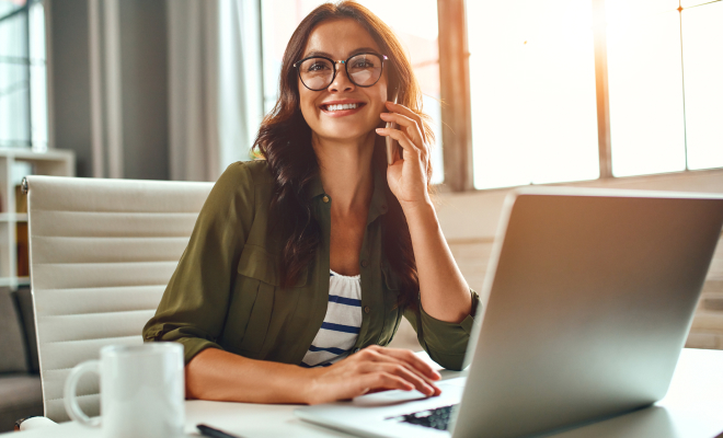 Mulher sorrindo com a mão na bochecha, mexendo no computador