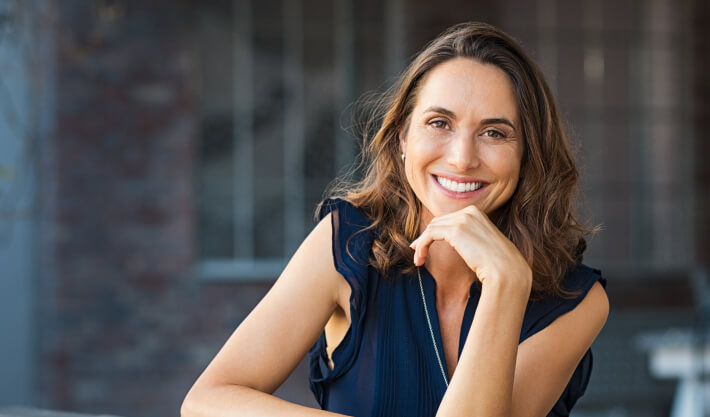 Mulher sorrindo com a mão no queixo